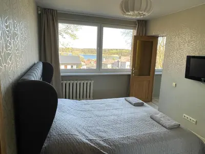 a bedroom with a bed and a large window at Central place with lake view in Šiauliai