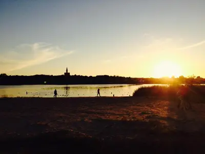 a group of people playing on the beach at sunset at Central place with lake view in Šiauliai