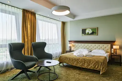 a hotel room with a bed and two chairs at Grand SPA Lietuva Hotel Lietuva in Druskininkai