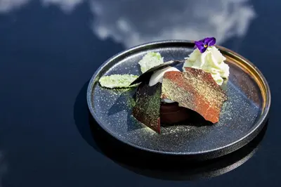 a plate with a piece of cake and whipped cream at Grand SPA Lietuva Hotel Lietuva in Druskininkai