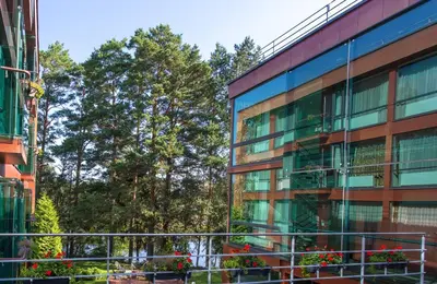 an office building with trees in the background at MEDEA Apartments by UPA in Druskininkai