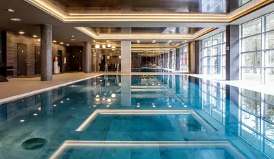 a swimming pool with blue water in a building at MEDEA Apartments by UPA in Druskininkai
