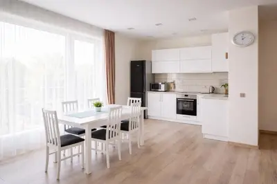 a kitchen with a table and chairs and a kitchen with white cabinets at Ąžuolo apartamentai in Birštonas