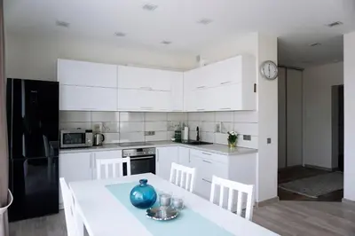 a kitchen with white cabinets and a table and chairs at Ąžuolo apartamentai in Birštonas
