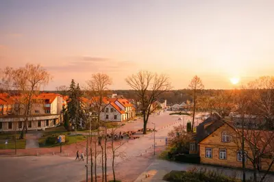 an old town at sunset with the sun setting at Ąžuolo apartamentai in Birštonas