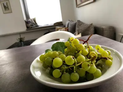 a bowl of green grapes on a table at Vilnius apartment with stained glass in Vilnius