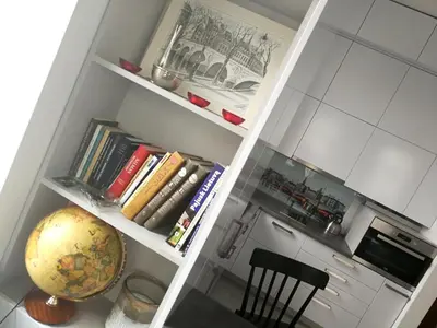 a kitchen with white cabinets and a shelf with books at Vilnius apartment with stained glass in Vilnius
