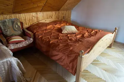 a wooden bed in a room with a chair at Svečiuose pas Aldoną in Druskininkai