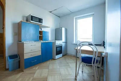 a kitchen with blue cabinets and a table and a chair at Svečiuose pas Aldoną in Druskininkai