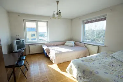 a bedroom with two beds and a tv and two windows at Svečiuose pas Aldoną in Druskininkai
