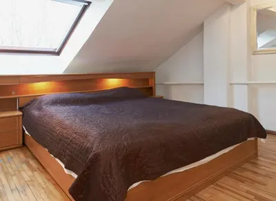 a bedroom with a bed with a wooden headboard and a window at Regina House- sv. Mikalojaus 13 in Vilnius