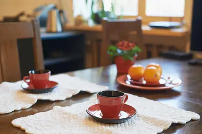 a wooden table with two cups and oranges on plates at Regina House- sv. Mikalojaus 13 in Vilnius