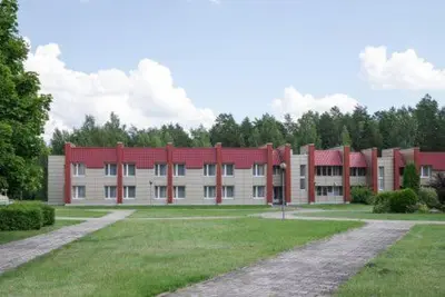 a large brick building with a red roof at Visagino parkas in Visaginas