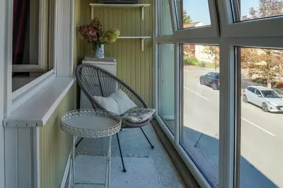 a wicker chair sitting on a porch next to a window at Apartamentai Birštono centre su židiniu in Birštonas