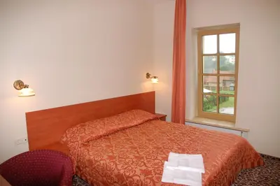 a bedroom with a bed and a window at Hotel-Restaurant Smilga in Kėdainiai