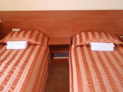 two beds in a hotel room with white towels at Hotel-Restaurant Smilga in Kėdainiai
