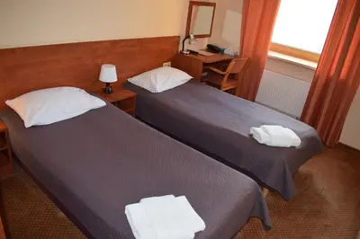 two beds in a hotel room with towels on them at Hotel-Restaurant Smilga in Kėdainiai