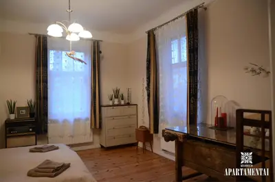 a bedroom with a bed and a desk and a window at Senamiesčio APARTAMENTAI in Panevėžys