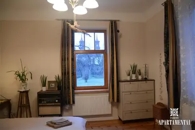a bedroom with a window and a dresser and a bed at Senamiesčio APARTAMENTAI in Panevėžys