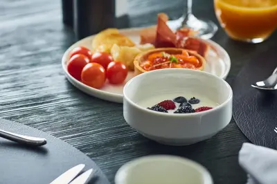 a table with a bowl of fruit and a plate of food at Hotel Pacai, Vilnius, a Member of Design Hotels in Vilnius