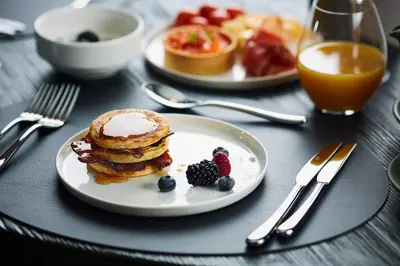 two plates of pancakes and berries on a table at Hotel Pacai, Vilnius, a Member of Design Hotels in Vilnius