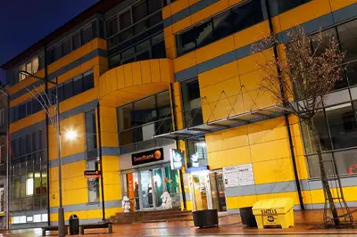 a yellow and black building with a gas station at Litrada Apartments in Šiauliai