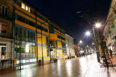 a city street at night with a yellow building at Litrada Apartments in Šiauliai
