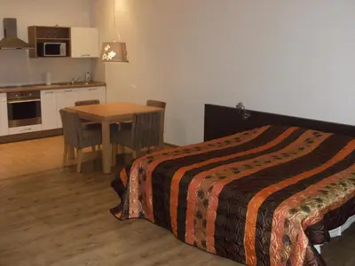 a bedroom with a bed and a table and a kitchen at Litrada Apartments in Šiauliai
