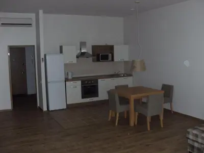 a kitchen with a table and a white refrigerator at Litrada Apartments in Šiauliai