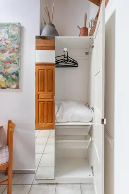 a small closet with white shelves in a room at House of Sun in Vilnius