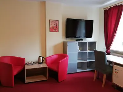 a living room with red chairs and a flat screen tv at Idilė Bed & Breakfast - Visaginas in Visaginas