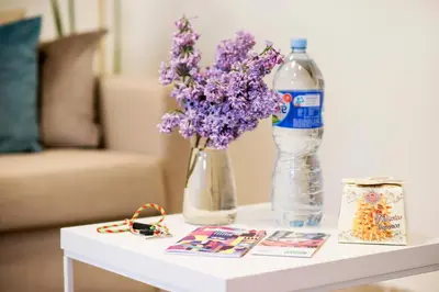 a table with a bottle of water and a vase of purple flowers at Stay in Kaunas - Free Parking in Kaunas