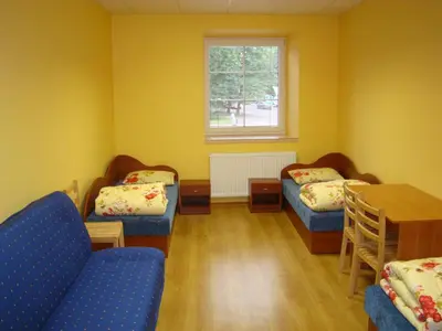 a room with two beds and a table and a window at Fortuna Hostel in Vilnius