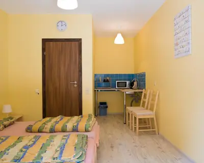 a room with two beds and a desk with a microwave at Fortuna Hostel in Vilnius