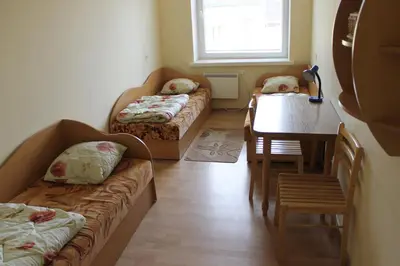 a room with two beds and a table and a dining room at Fortuna Hostel in Vilnius