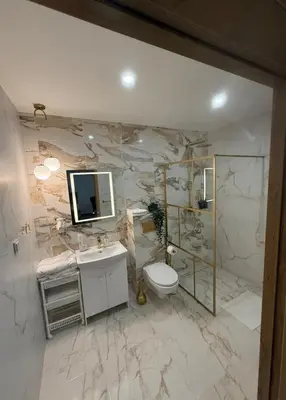 a bathroom with a toilet and a television on the wall at Simona House in Šiauliai