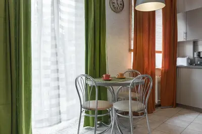 a table and chairs in a kitchen with green curtains at Natalex Europe in Vilnius