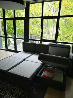 a couch sitting in a room with windows at Loft on Owl Hill in Kaunas