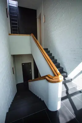 a staircase in a building with a wooden rail at Loft on Owl Hill in Kaunas