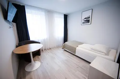 a small room with a bed and a table and a television at Dzūkija Hotel in Alytus