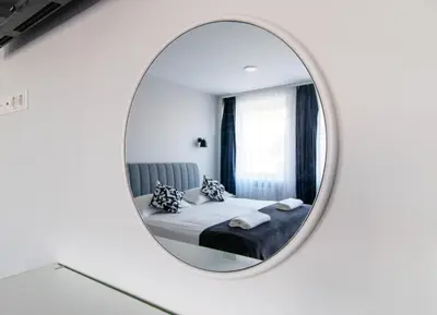 a bedroom with a bed and a round mirror at Dzūkija Hotel in Alytus