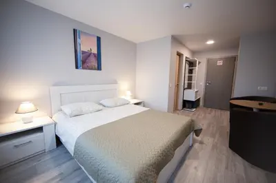 a bedroom with a white bed and two lamps and a table at Dzūkija Hotel in Alytus