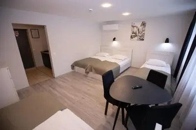 a small room with two beds and a table at Dzūkija Hotel in Alytus