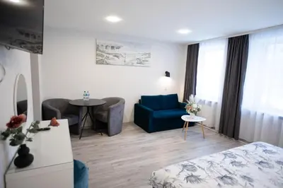 a living room with a blue couch and a table at Dzūkija Hotel in Alytus