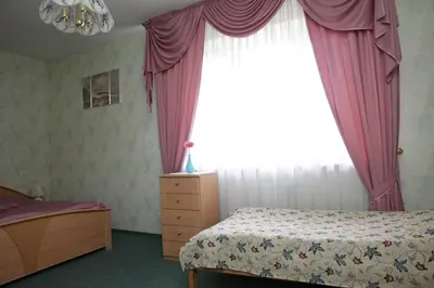 a bedroom with a bed and a window with pink curtains at Guest House Linas in Alytus