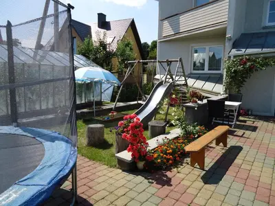 a backyard with a playground with a slide and flowers at Guest House Linas in Alytus