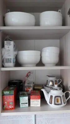 a shelf with bowls and dishes and a tea kettle at Gražinos apartamentai in Panevėžys