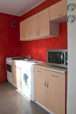 a kitchen with a washing machine and a microwave at Old Town Apartments in Alytus