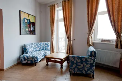 a living room with two chairs and a table and windows at Old Town Apartments in Alytus