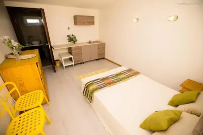a bedroom with a bed and a desk and a yellow chair at Old Town Apartments in Alytus